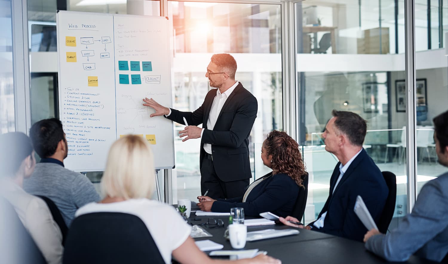 Presenter in a suit points to a whiteboard