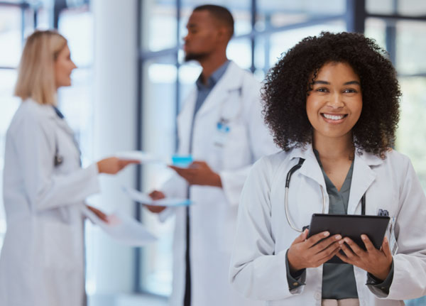 Student in lab coat smiling towards viewer.